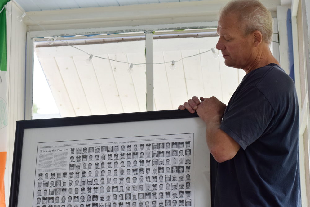 Mr. Brickman holds a display of a 2001 spread in The New York Times that featured every fallen firefighter on 9/11. (Credit: Joe Werkmeister)