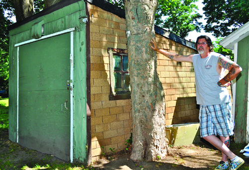 GIANNA VOLPE PHOTO | Richard Hardt next to the garage he said his great-grandfather Mervin Baker assembled with lumber left over from the building of Brecknock Hall in Greenport.