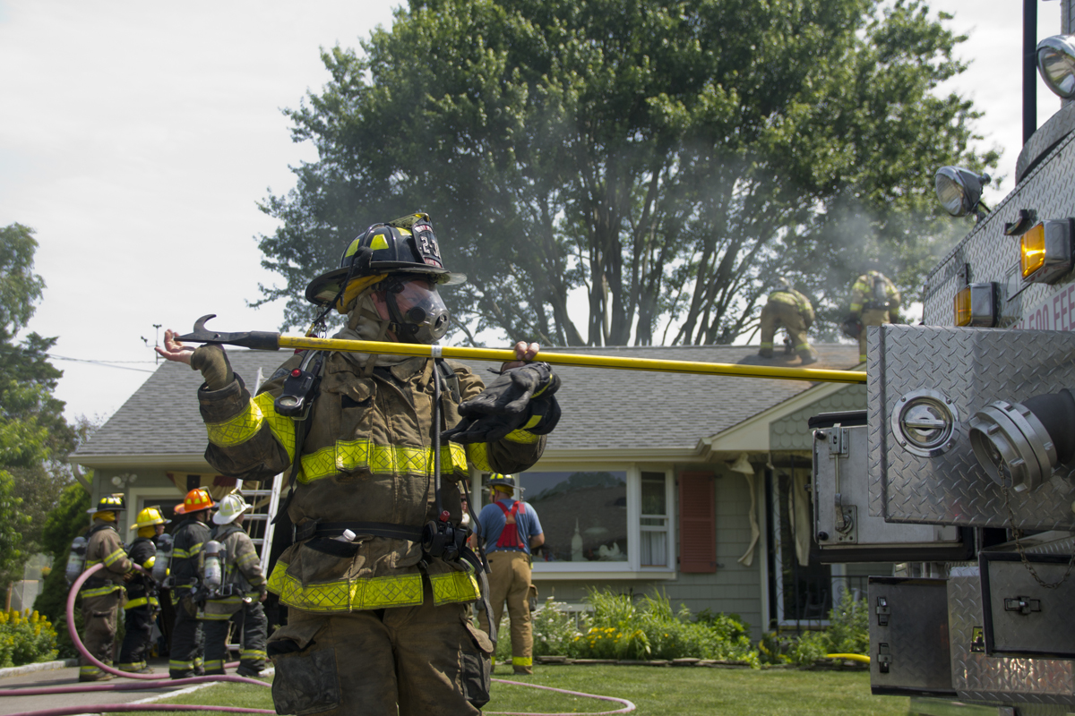 An East Marion firefighter grabs equipment from one of the fire trucks as volunteers knock down a house fire Thursday morning. (Credit: Paul Squire)