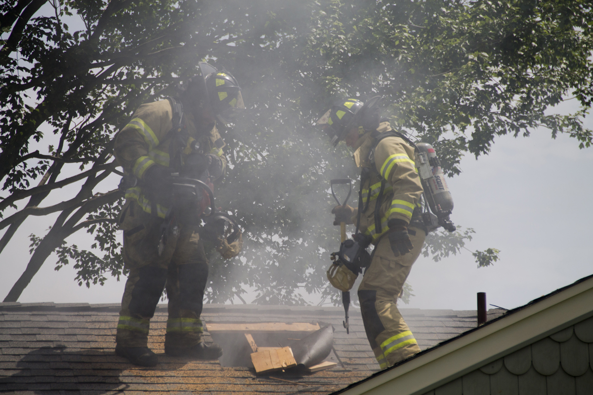 Volunteers tear up part of the burning home's roof to access the fire. (Credit: Paul Squire)