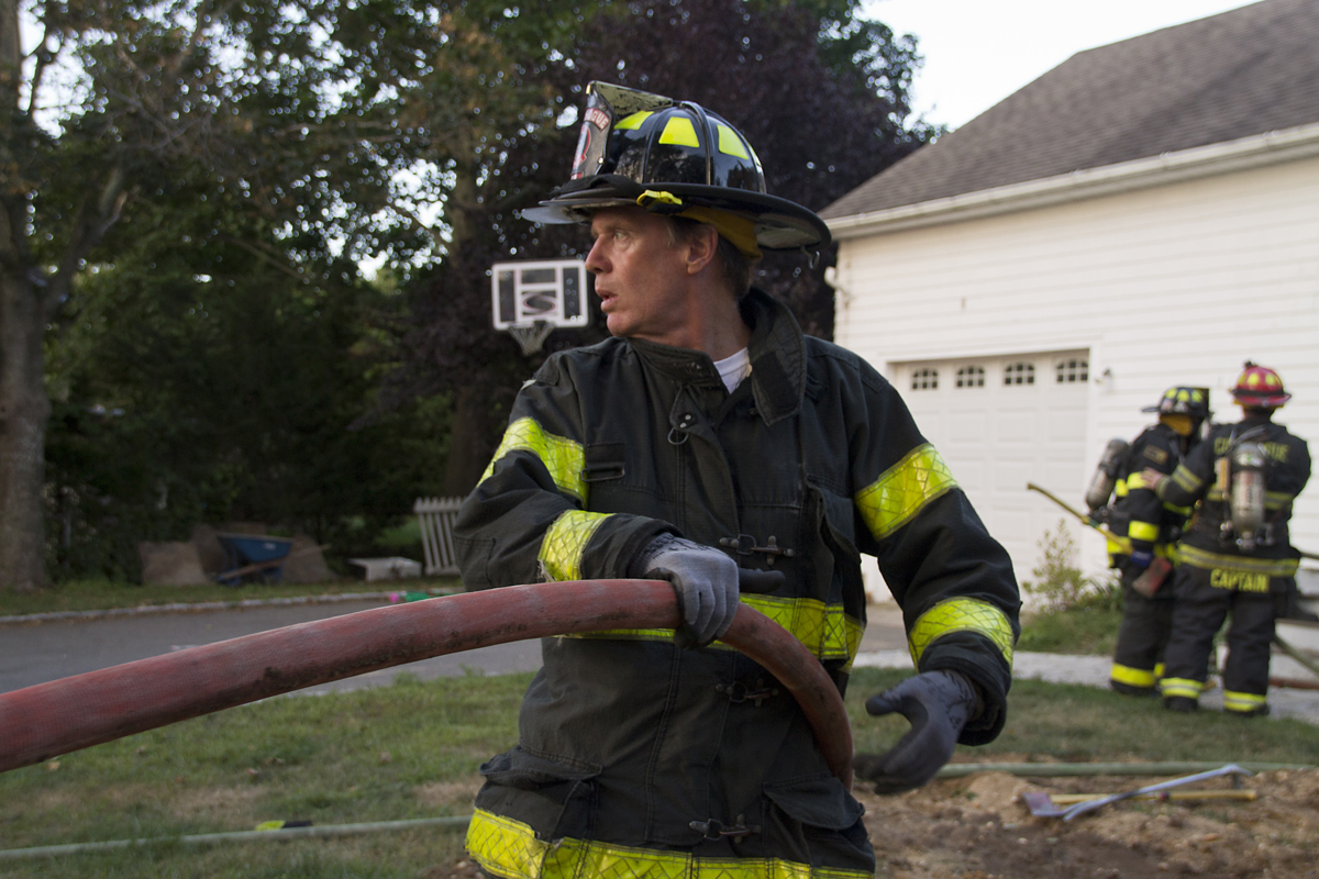 A Cutchogue firefighter helps lead a fire hose into the department's training scene Wednesday evening (Credit: Paul Squire)