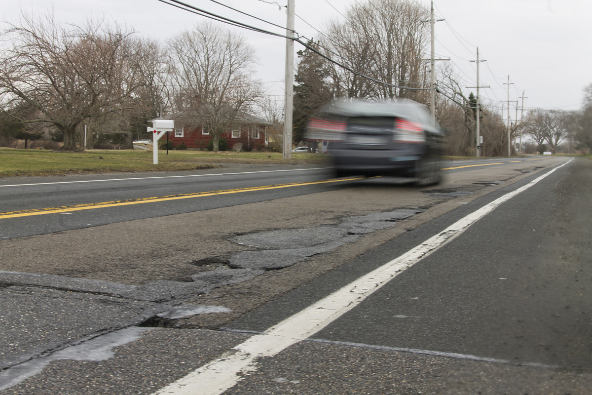 A driver speeds by a smattering of potholes on Route 48 in Southold Friday morning. (Credit: Paul Squire)