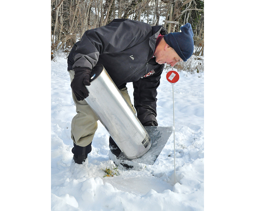 TIM KELLY PHOTO | Lenny Llewellyn demonstrates snow-measuring equipment at his Mattituck home.