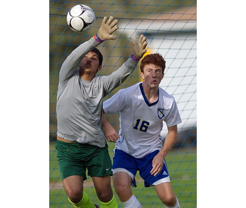 Wyandanch goalkeeper Jose Reyes gets a piece of a corner kick in the vicinity of Mattituck's Tim Schmidt. (Credit: Garret Meade)