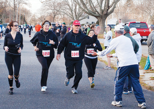 KATHARINE SCHROEDER PHOTO | Pete Orlowski approaches the finish line accompanied by, from left, his daughter Jacy, his wife Debbie, and his trainer Kerry Butler. KATHARINE SCHROEDER PHOTO | Pete Orlowski approaches the finish line accompanied by, from left, his daughter Jacy, his wife Debbie, and his trainer Kerry Butler.