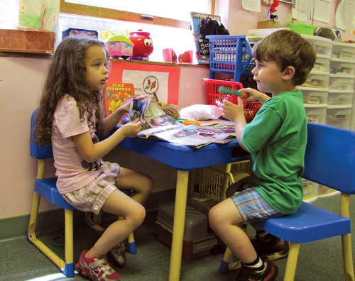 CYNDI MURRAY PHOTO | Two children read magazines at the Perry day care center in Greenport Friday.