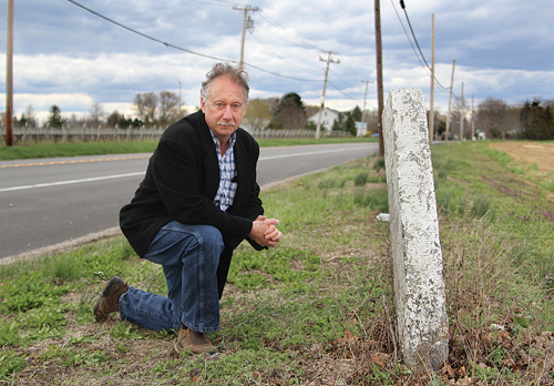 George Cork Maul, a Southold Town 375th Anniversary Committee member, in front of a mile markers along Main Road in Peconic. (Credit: Jen Nuzzo)